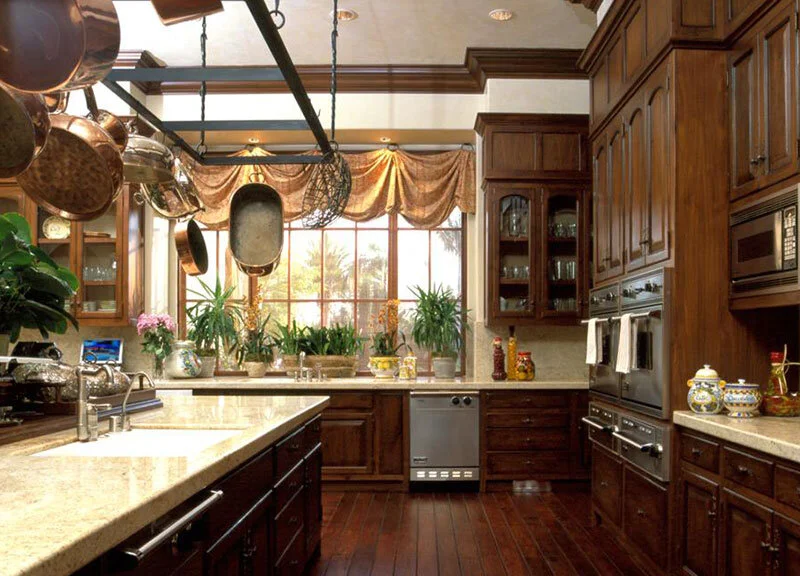 An Italian villa kitchen designed with lots of storage for a true cooks kitchen. The stained wood cabinets and flooring envelop you in a warm cozy embrace.