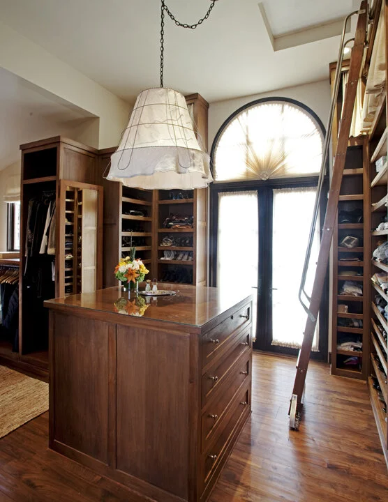 An open closet featuring wood shelves and a wooden dresser.  Items on the shelves are neatly arranged.