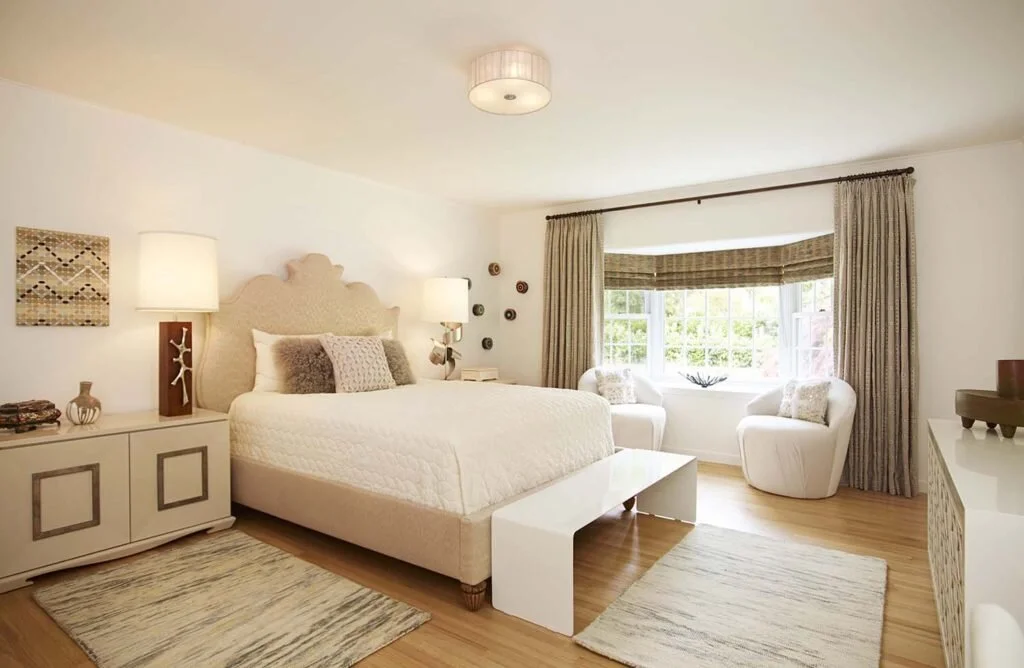 White bedroom color scheme with window seating and wooden floors.