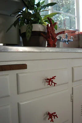 Cabinet hardware can have a big reward.  These white cabinets have knobs that look like red branches.