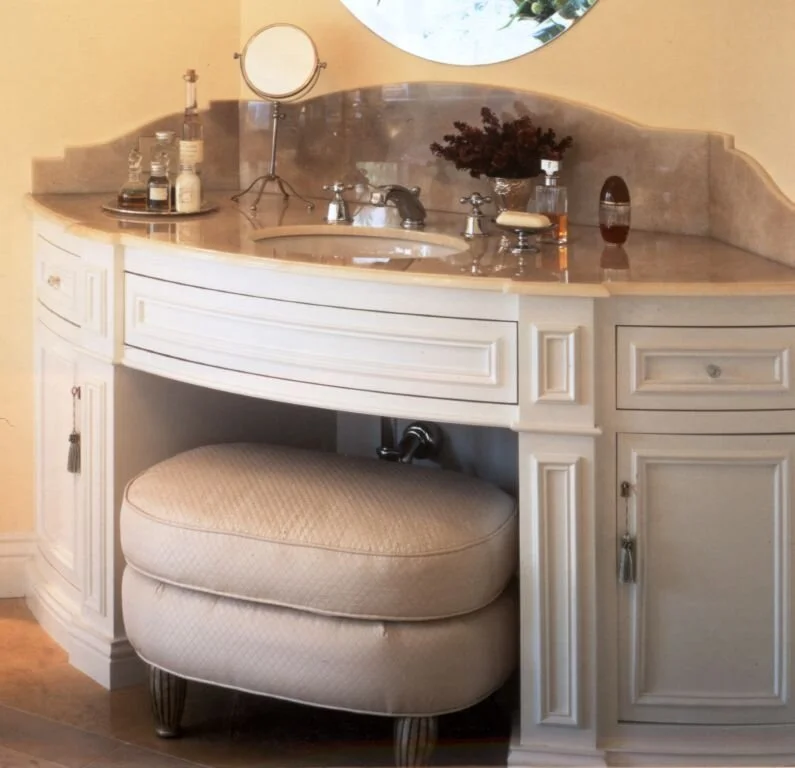 An organized bathroom vanity with a cushioned stool.