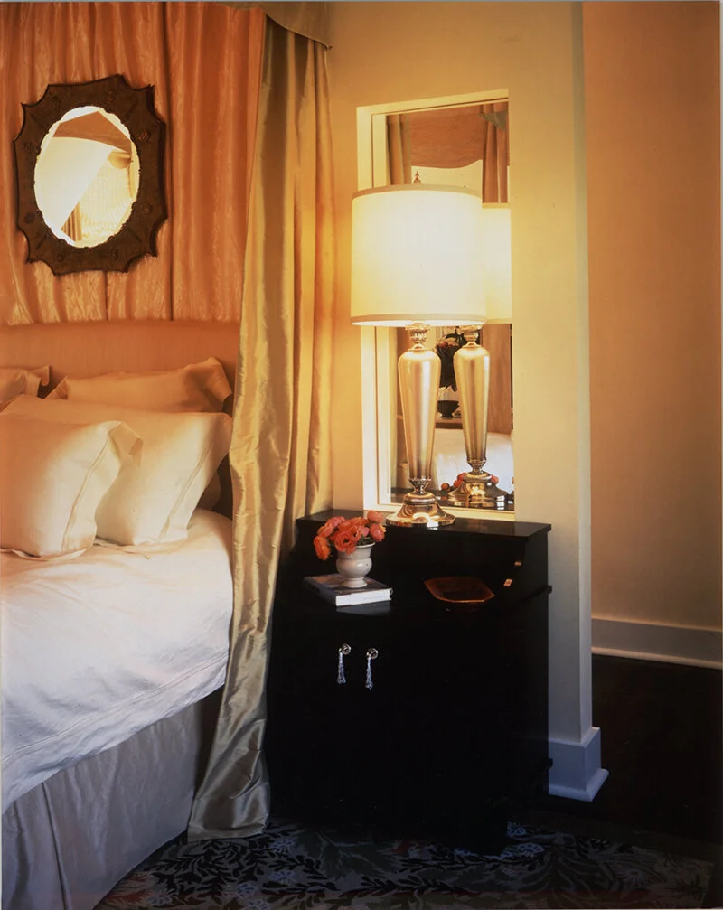 A bedroom as sanctuary with dim lighting and flowers on the nightstand.
