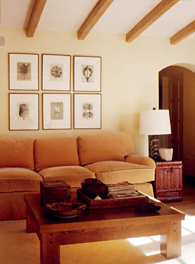 A family room with a comfortable upholstered sofa.  In front is a low wooden coffee table.