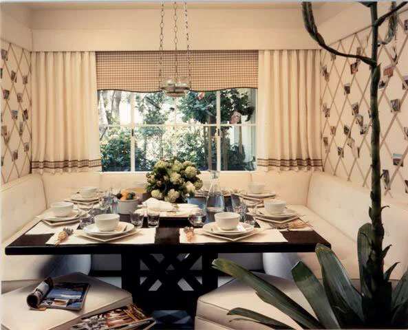 A small dining room banquette around a dark wood square table set for 8.