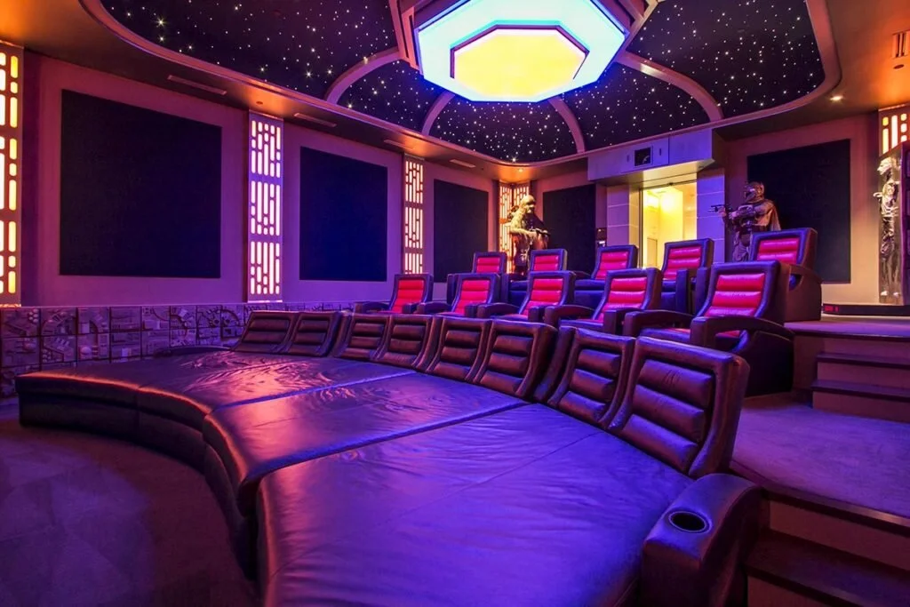 A large in home theater with neon lighting and theater seating.