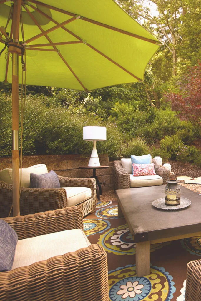 An outdoor space with comfortable wicker chairs, a low coffee table and a green umbrella.  Work from home outside and inject some fresh air into what you do.