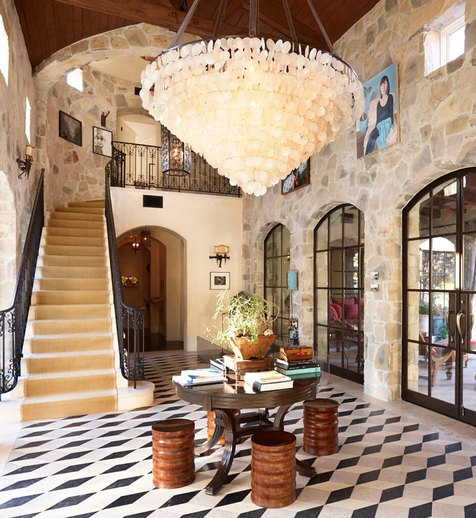 This modern French home entryway includes a large Capiz shell chandelier to soften the look of natural stone.
