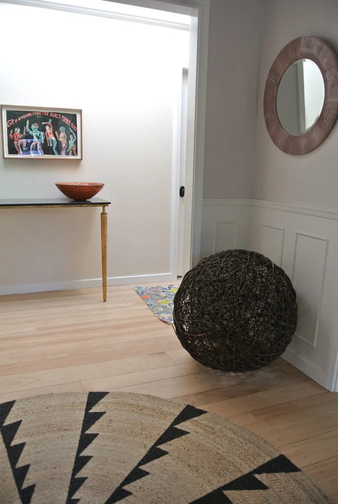 A minimalistic entryway in a bungalow features a rug and focal point and has an abstract art feel.