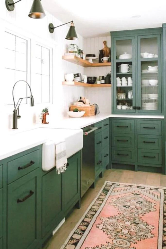 Kitchen cabinets painted a medium green color with white countertops and tiled walls.