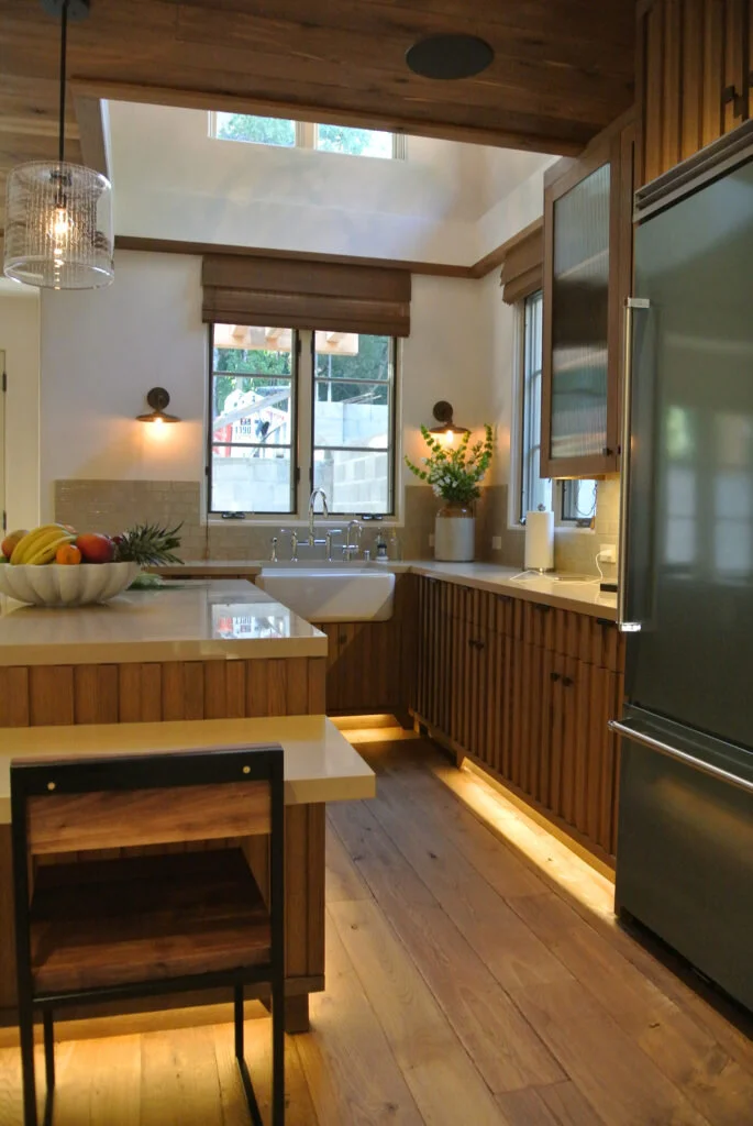 This transitional kitchen has a wood plant floor and a farmhouse sink. Designed by Mark Cutler Design.