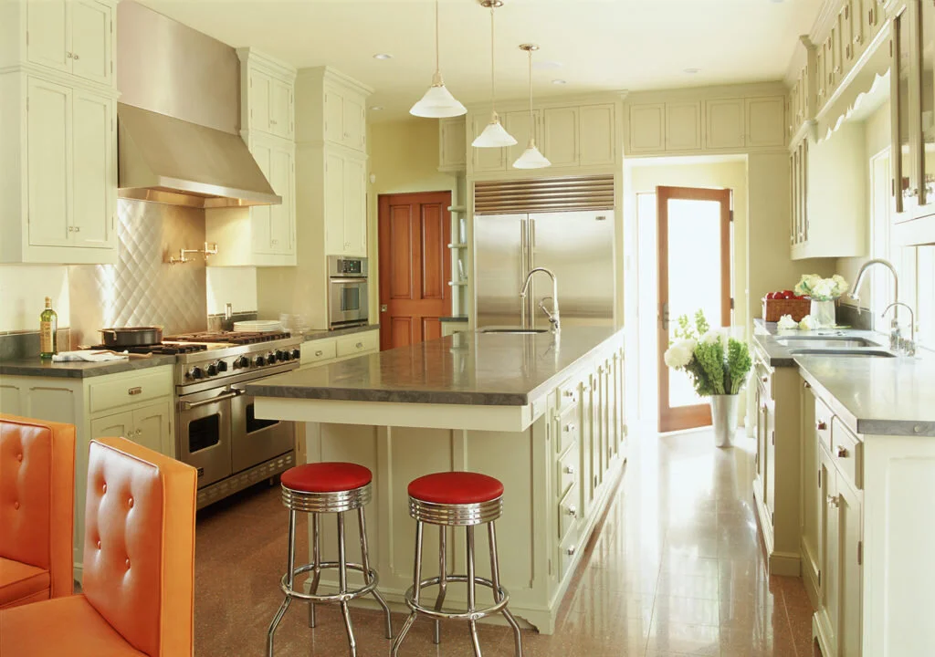 A beautiful white kitchen with orange accents and natural light. Designed by Mark Cutler Design.