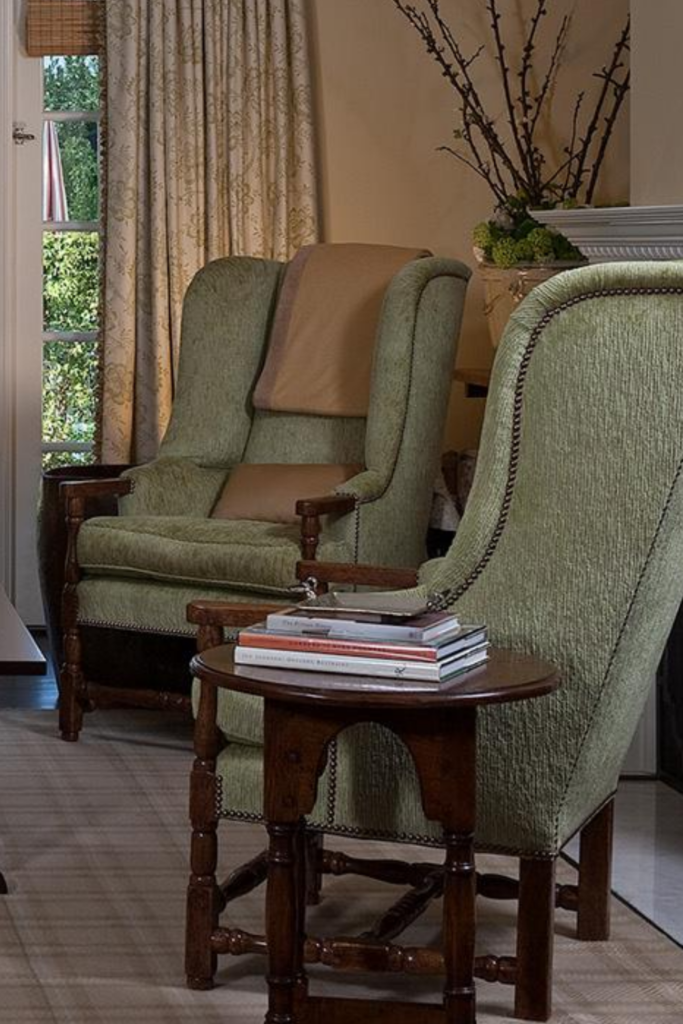 Two sage wing-back chairs with dark wood.  