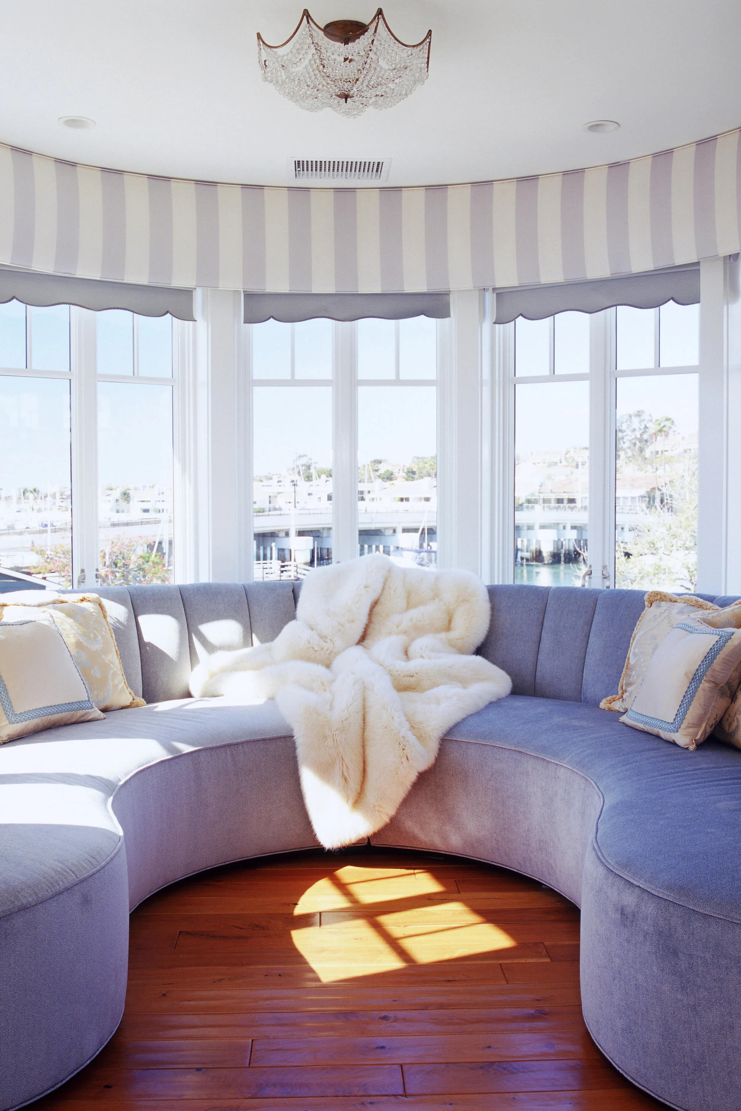 A curved window nook is lined with comfortable sofa seating and throw pillows.