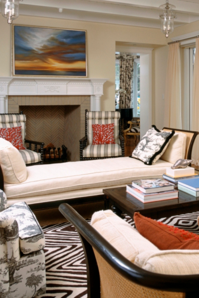 An eclectic living room with a chaise as a focal point. A painting of a sunset hangs above the fireplace.