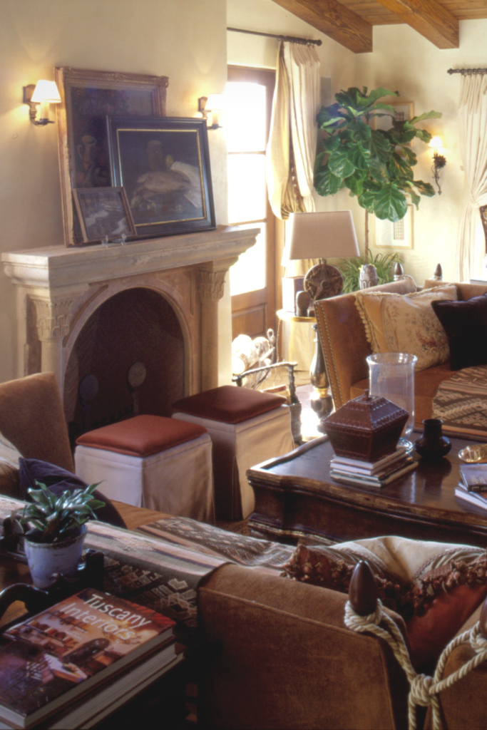 Several paintings are layered and stacked on a marble fireplace mantle.
