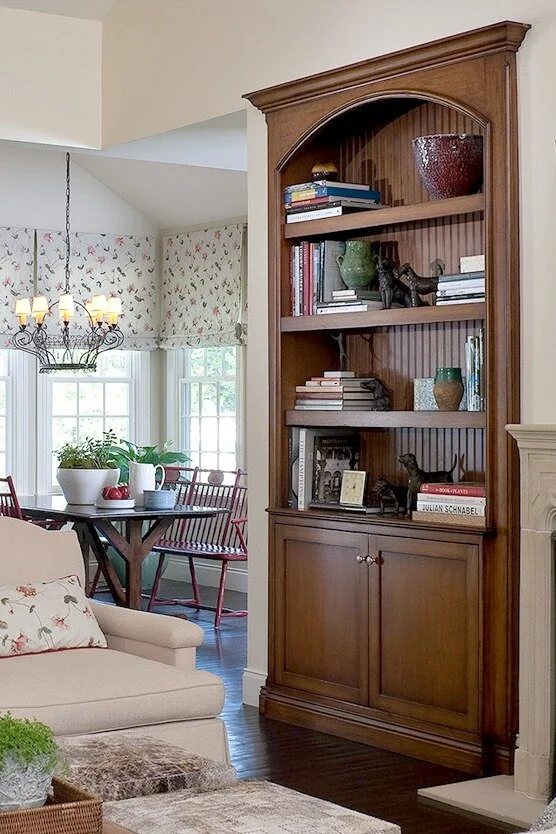Dark wood traditional bookshelf with a bead board back, accessorized with textured glazed pottery, books, and vintage iron dogs.