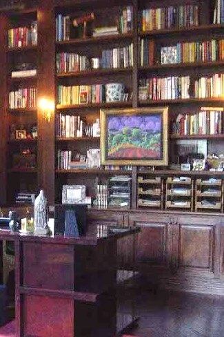 Library shelves inspired by old European rooms, stacked with books with electric sconces to enhance the look.